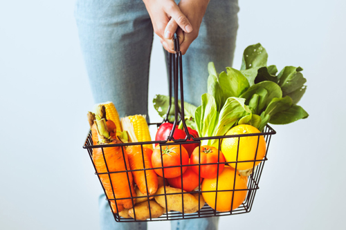 person holding a basket of fruits and vegetables